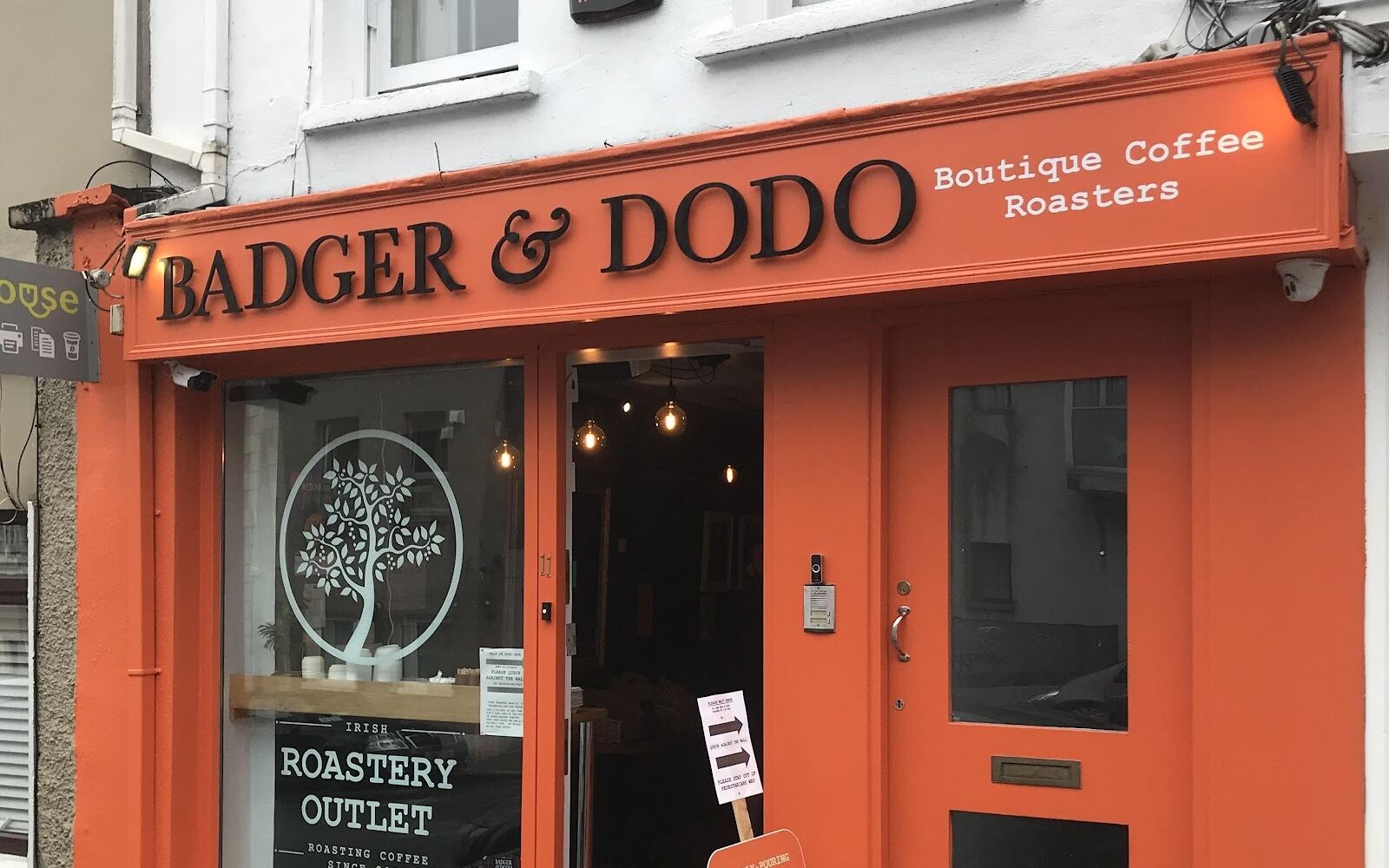 The orange shopfront of Badger & Dodo at 11 Barrack St, Cork, with the sign and the Irish Roastery Outlet window